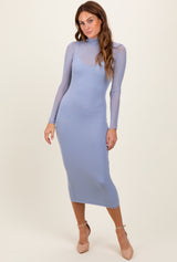 woman wearing a light blue fitted long sleeve dress with a high neckline and sheer overlay