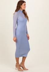 woman wearing a light blue long sleeve fitted dress with a mock neck and sheer overlay details