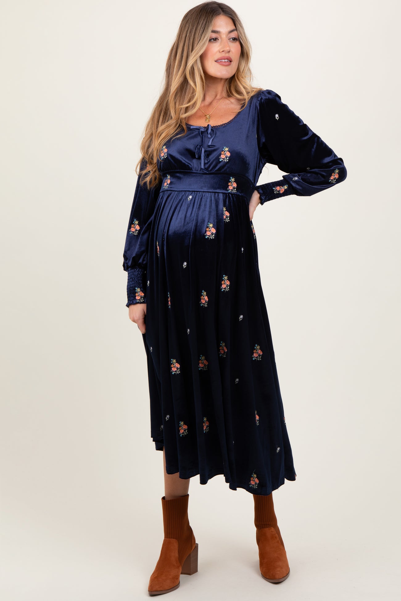 woman wearing a navy blue floral patterned maternity dress with long sleeves and a baby bump showing