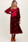 woman wearing a burgundy maternity dress with long sleeves and floral embroidery, showing a baby bump
