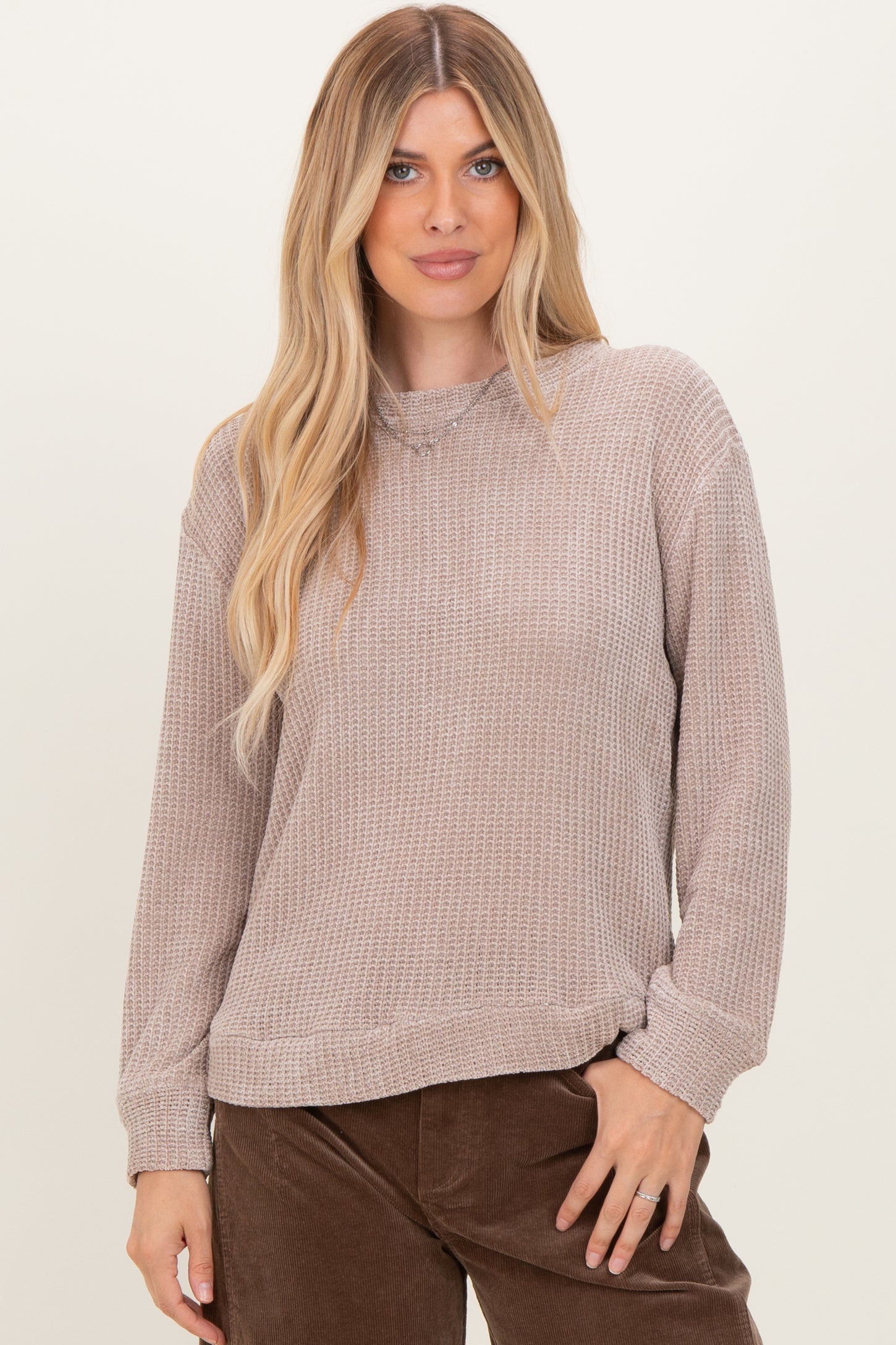 woman wearing a taupe long sleeve textured sweater with a relaxed fit and ribbed cuffs