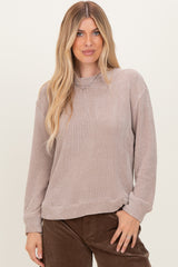 woman wearing a taupe long sleeve textured sweater with a relaxed fit and ribbed cuffs
