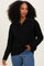 woman wearing a black zip-up sweater paired with blue jeans, showcasing a relaxed style and textured fabric