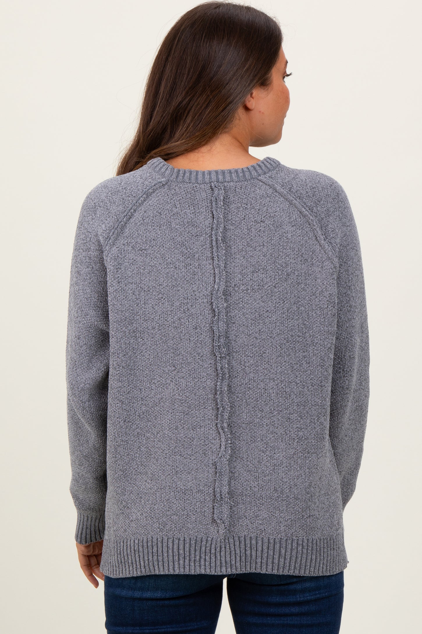 woman wearing a gray maternity sweater with a textured back detail, styled with long sleeves and a relaxed fit