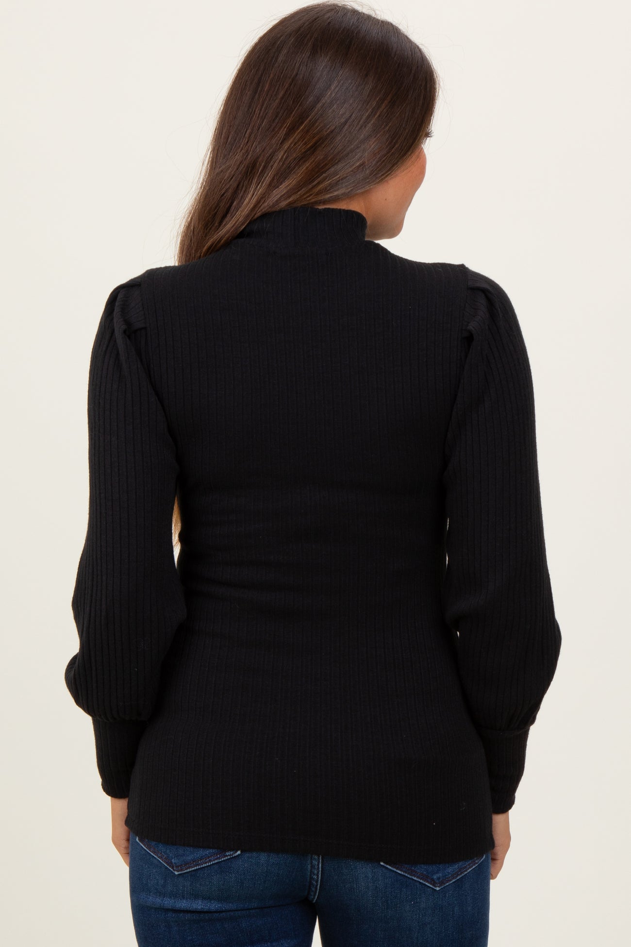 woman wearing a black ribbed maternity top with puff sleeves, viewed from the back