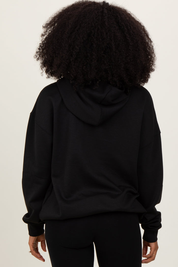 woman wearing a black oversized hoodie, viewed from the back with a relaxed fit and a hood