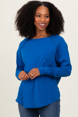 woman wearing a bright blue long sleeve top with a rounded neckline and relaxed fit, paired with jeans