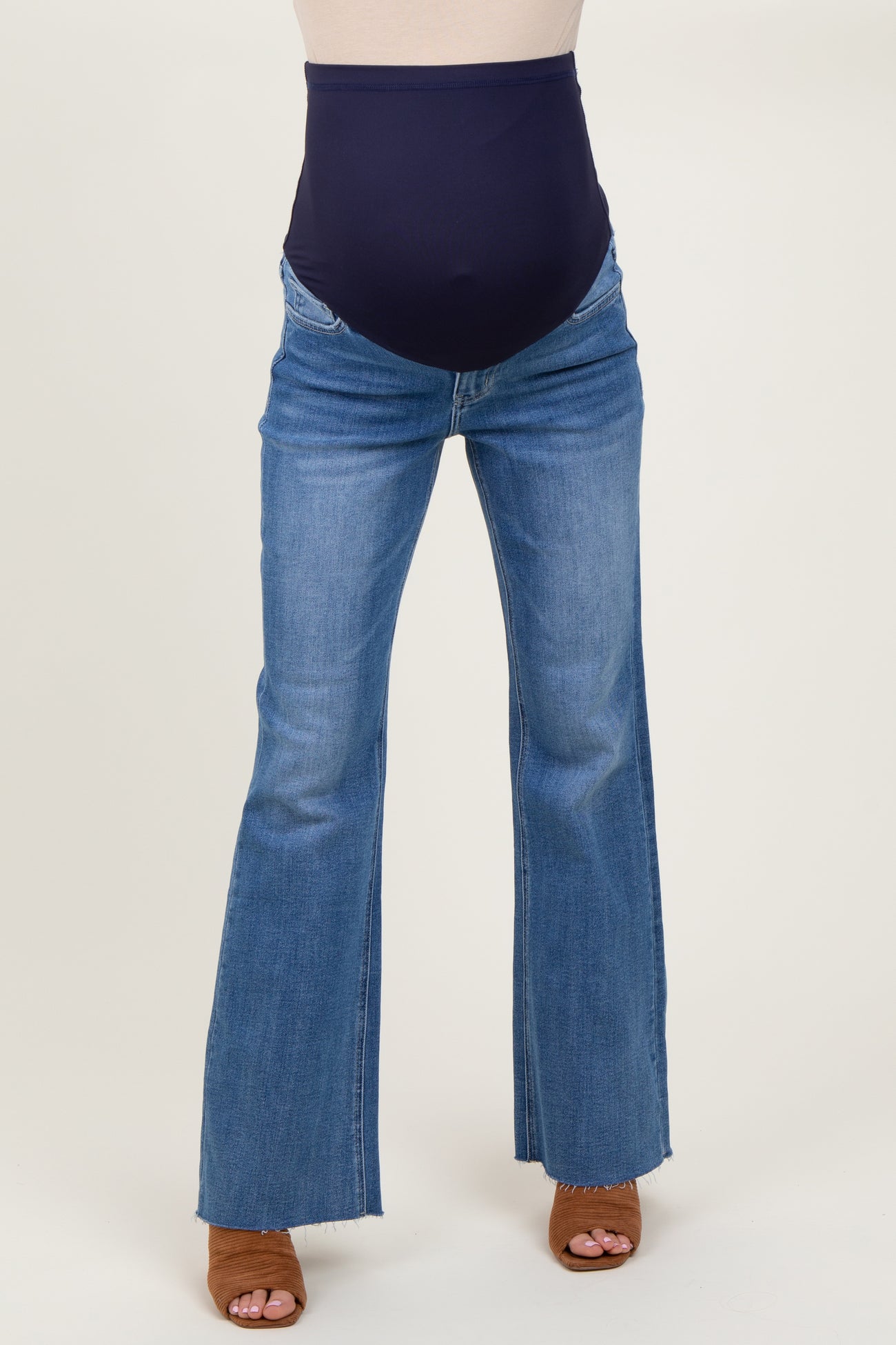 woman wearing a pair of blue flared maternity jeans with a navy band at the waist