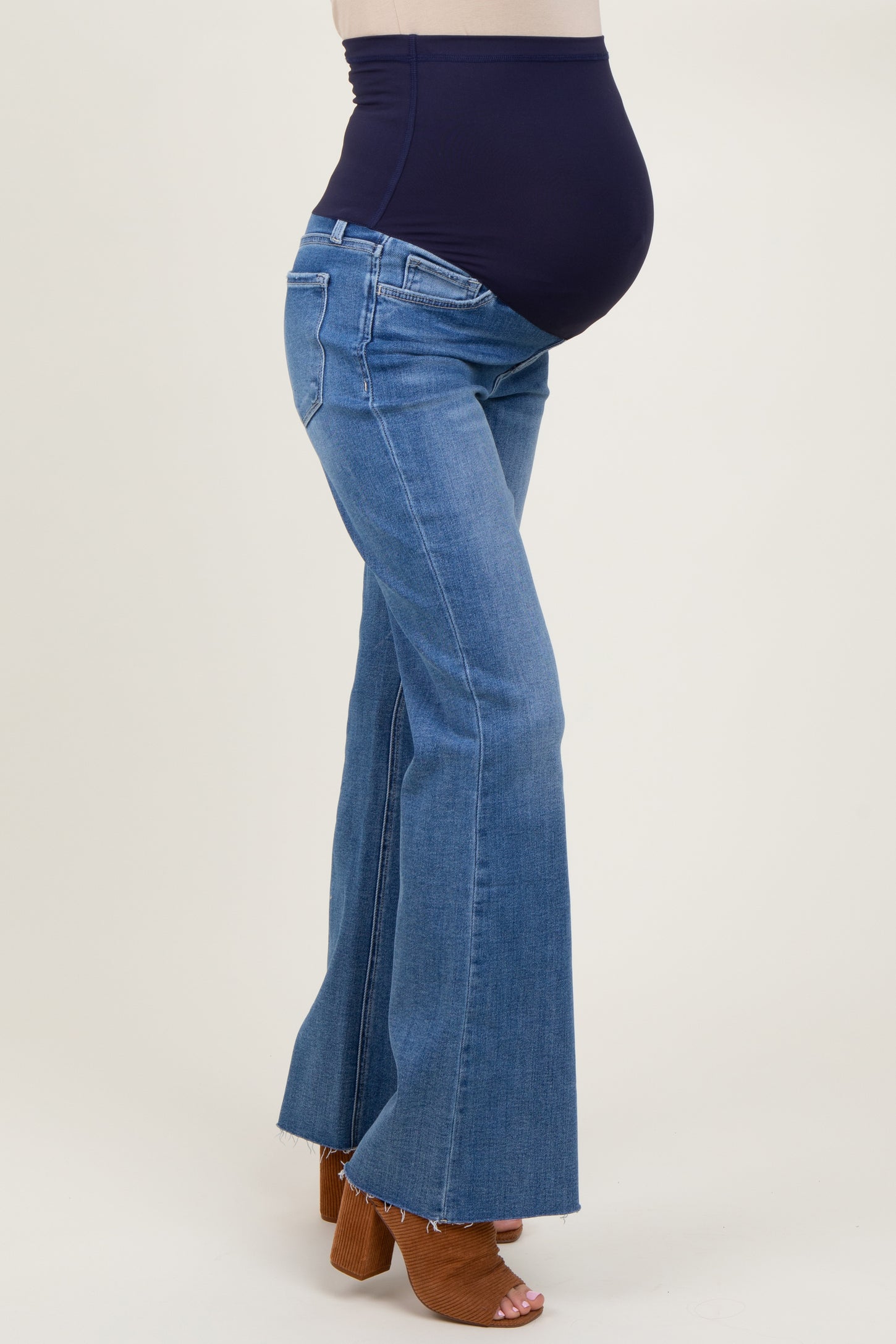 woman wearing dark blue maternity flared jeans with a high waistband and visible baby bump