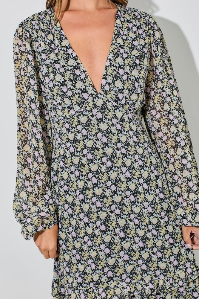 woman wearing a black floral long sleeve dress with a deep v-neck and loose, flowing sleeves