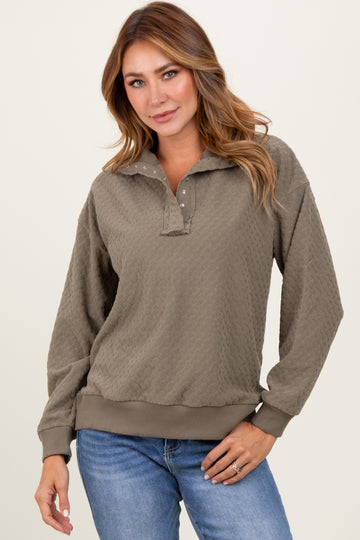 woman wearing a olive green textured pullover with a collar and button details, paired with blue jeans