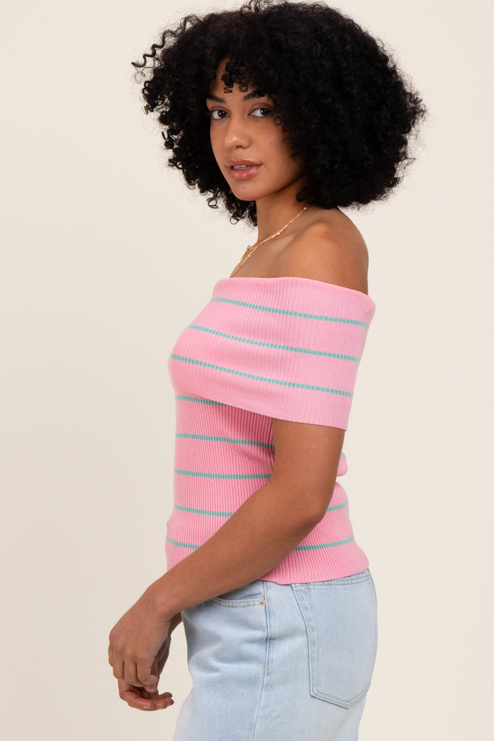 woman wearing a pink off-the-shoulder ribbed top with teal stripes and light blue high-waisted jeans