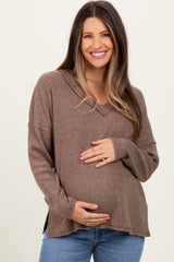 woman wearing a brown ribbed maternity sweater and holding her baby bump