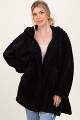 woman wearing a black oversized hooded cozy cardigan with pockets and textured fabric