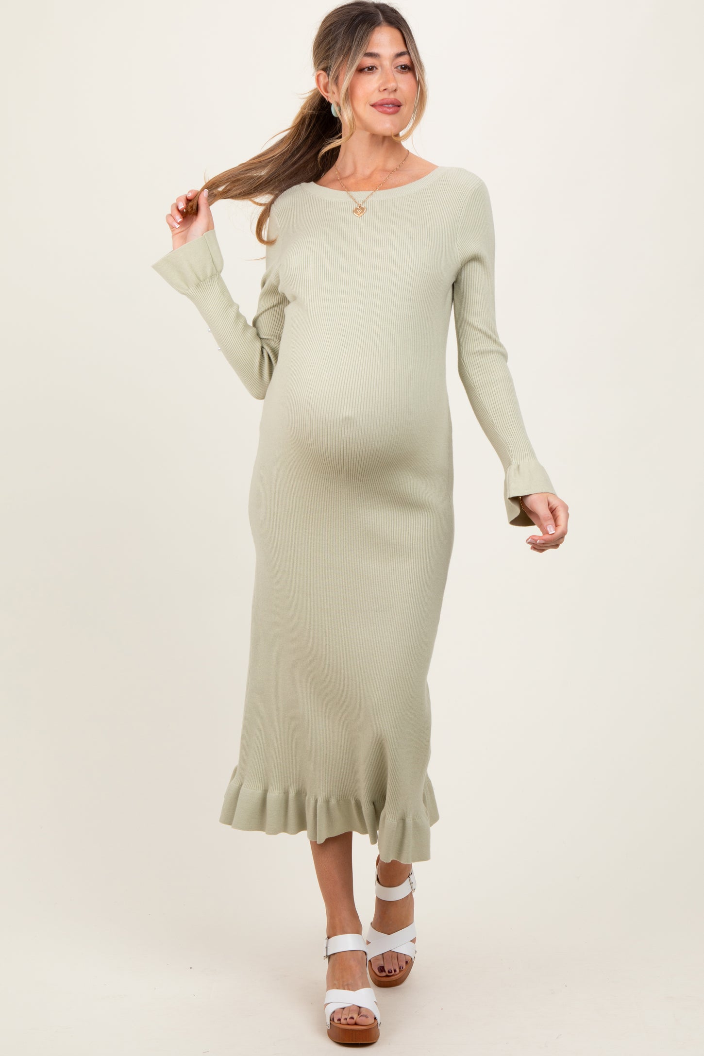 woman wearing a light green ribbed maternity dress with a ruffled hem and a visible baby bump