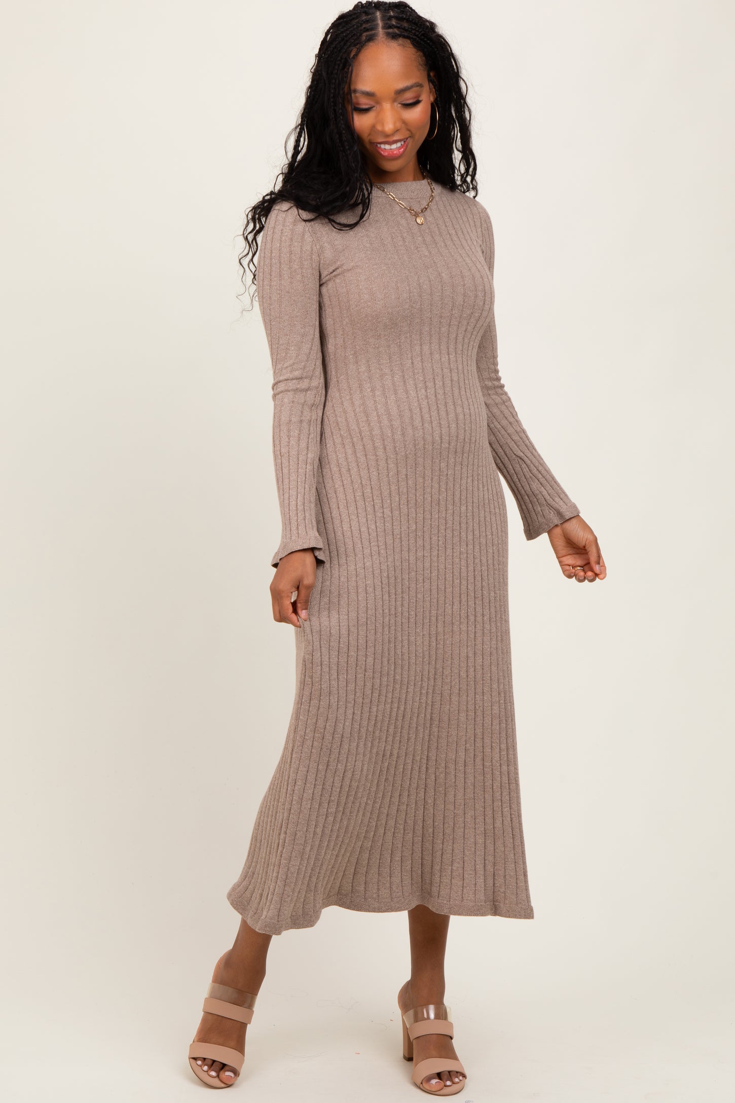 woman wearing a taupe ribbed midi dress with long sleeves and a fitted silhouette, paired with beige block-heeled sandals