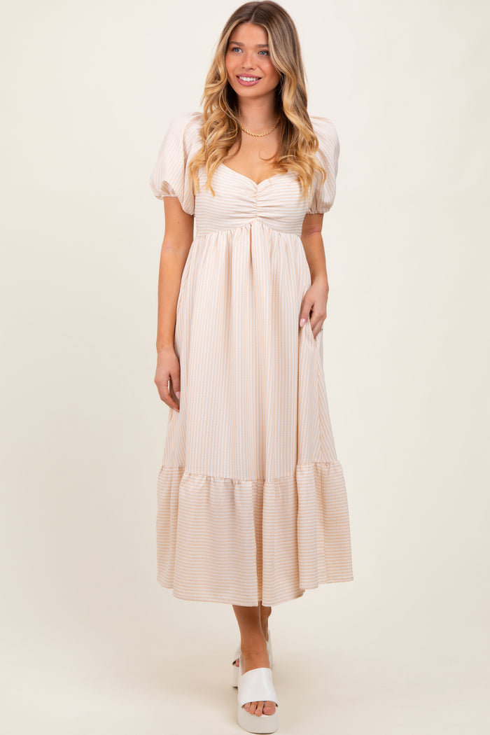 woman wearing a light beige striped puff sleeve maxi dress with a gathered bodice and tiered hem