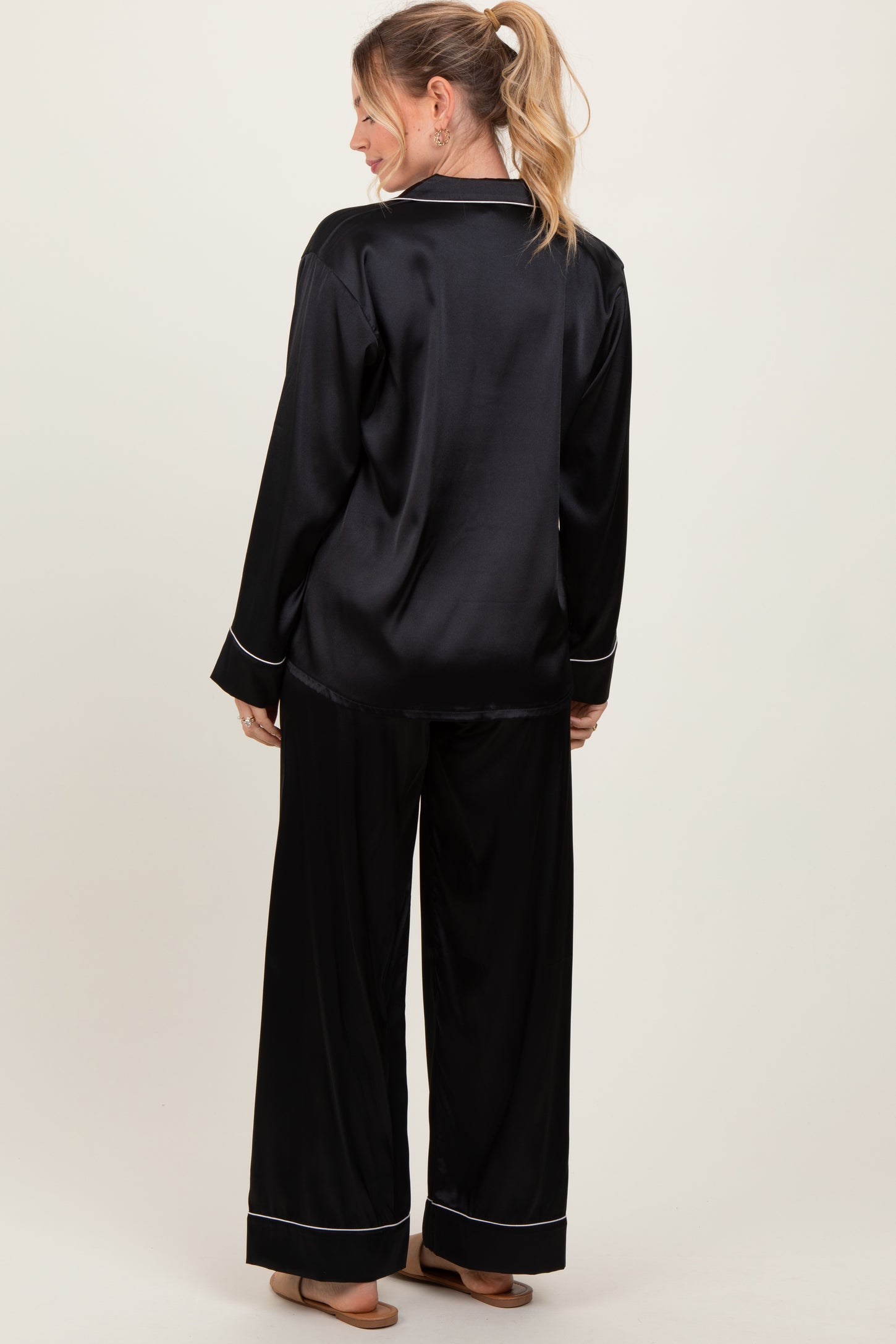 woman wearing a black satin pajama set with long sleeves and wide-leg pants, shown from the back
