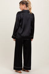 woman wearing a black satin pajama set with long sleeves and wide-leg pants, shown from the back