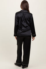 woman wearing a black satin maternity pajama set with long sleeves and matching pants, seen from the back