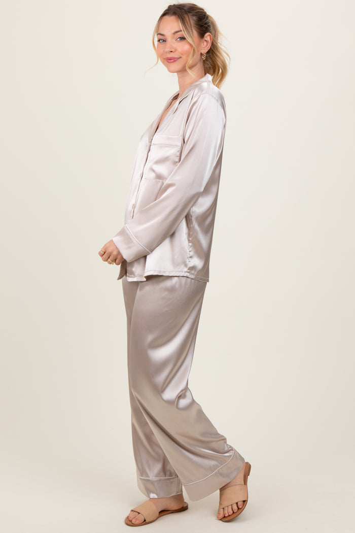 woman wearing a light beige satin pajama set with long sleeves and loose-fitting pants