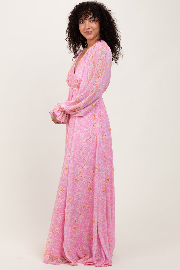 woman wearing a pink long sleeve maxi dress with floral prints and a tie neckline