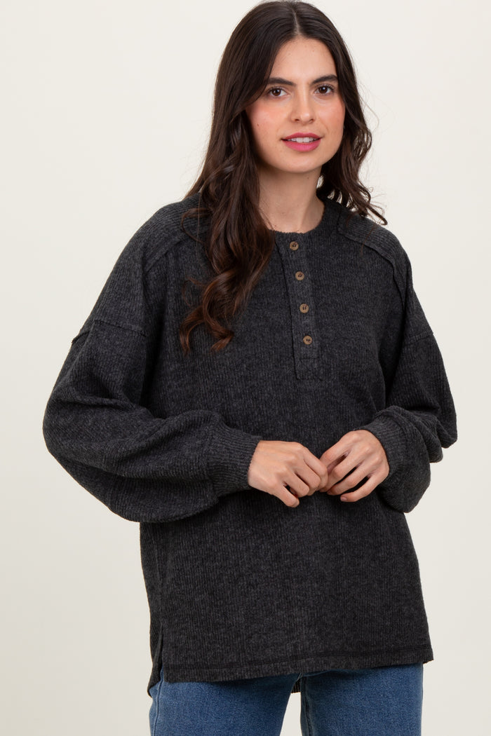 woman wearing a dark gray oversized henley sweater with buttons and balloon sleeves