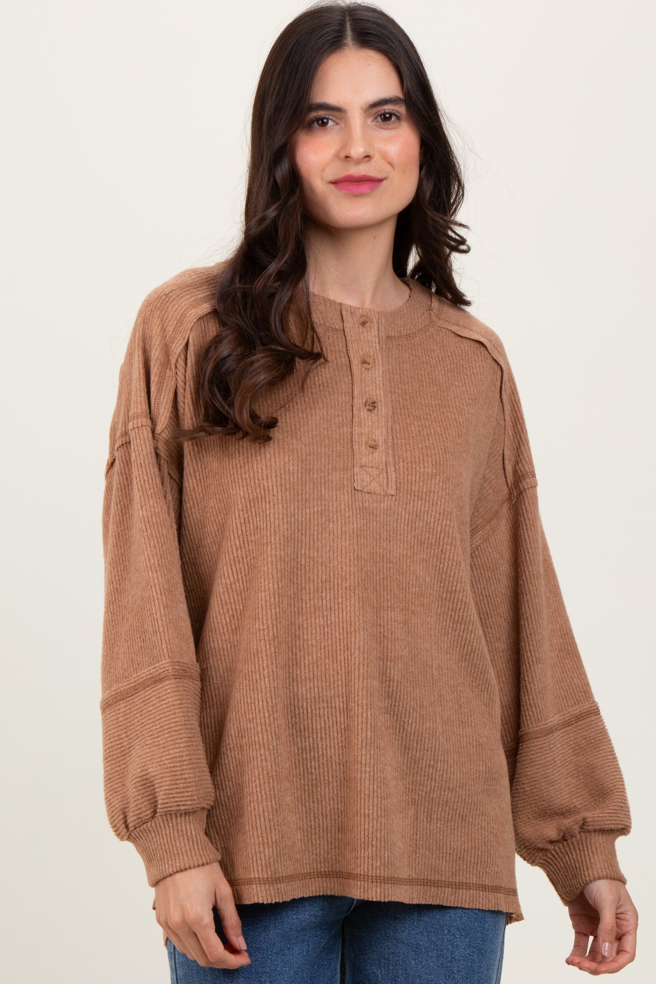 woman wearing a tan ribbed oversized henley top with button details and balloon sleeves