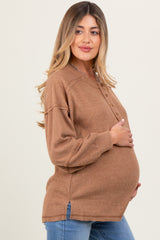 woman wearing a brown ribbed maternity top with buttons, showing off her baby bump while posing sideways