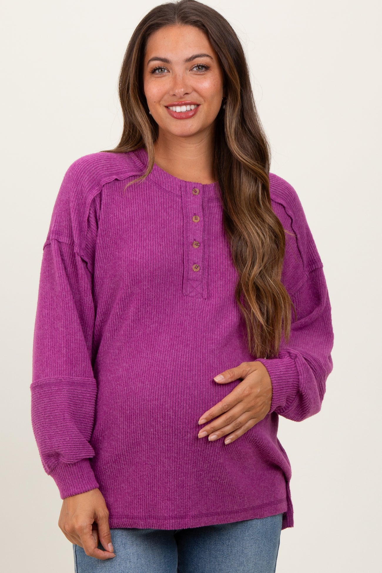 woman wearing a purple maternity henley top with button details and holding her baby bump