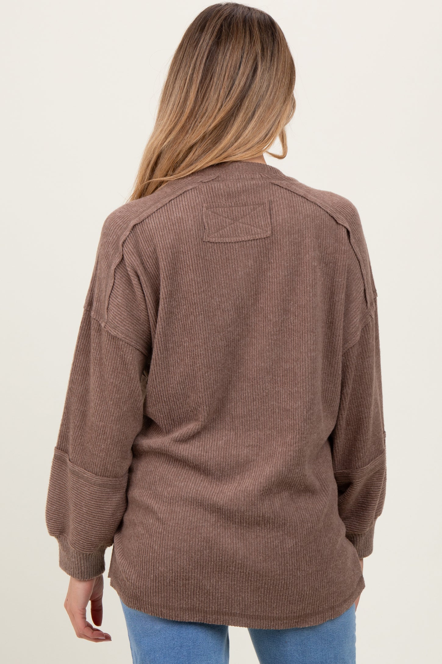 woman wearing a brown ribbed maternity sweater with a relaxed fit and dropped shoulders, seen from the back