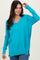 woman wearing a vibrant turquoise long sleeve v-neck sweater with side slits and relaxed fit