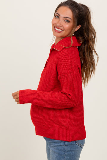 woman wearing a red collared maternity sweater, smiling and showing her baby bump
