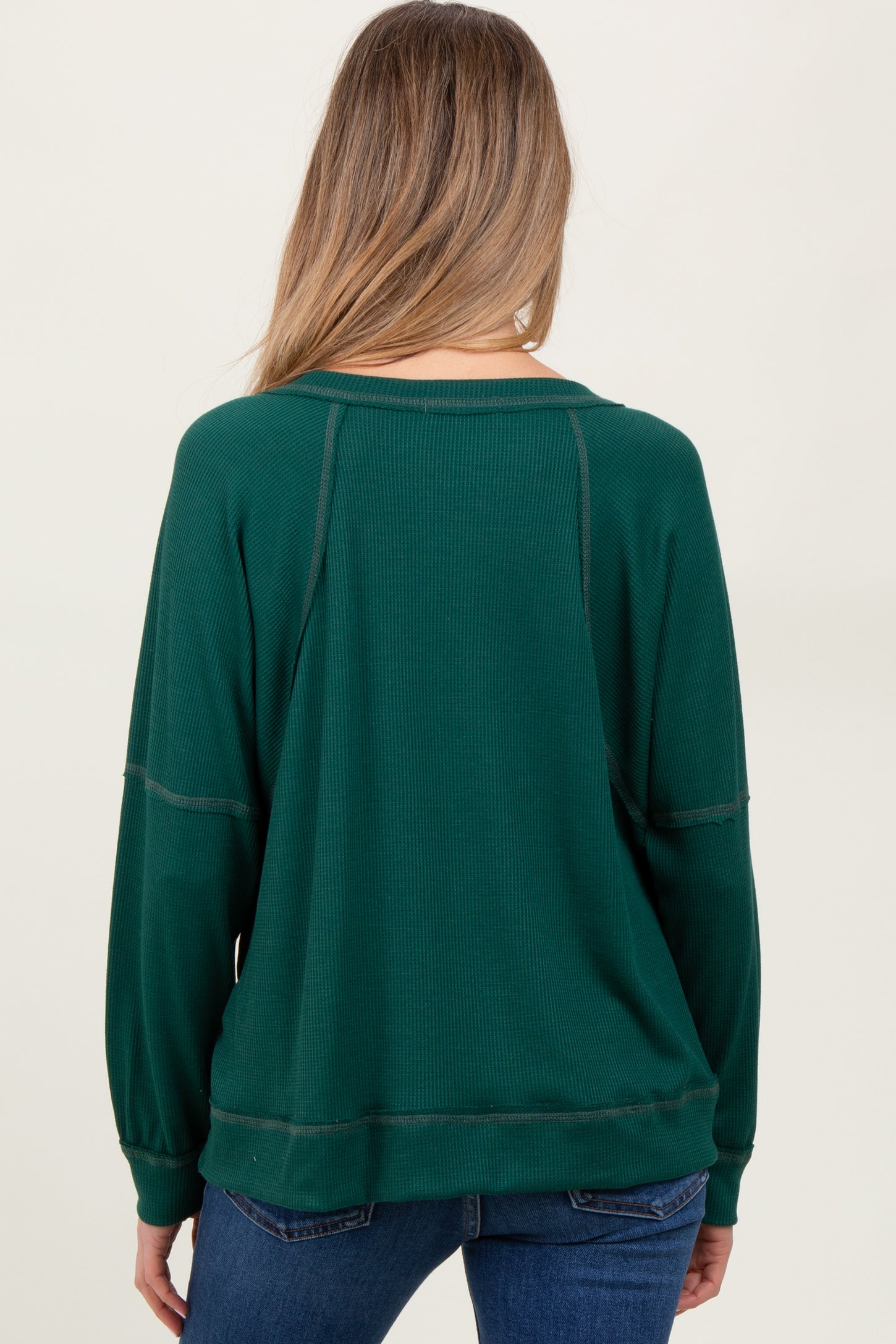 woman wearing a dark green maternity sweatshirt with a relaxed fit and ribbed texture, showing the back view