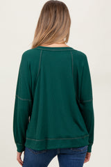 woman wearing a dark green maternity sweatshirt with a relaxed fit and ribbed texture, showing the back view