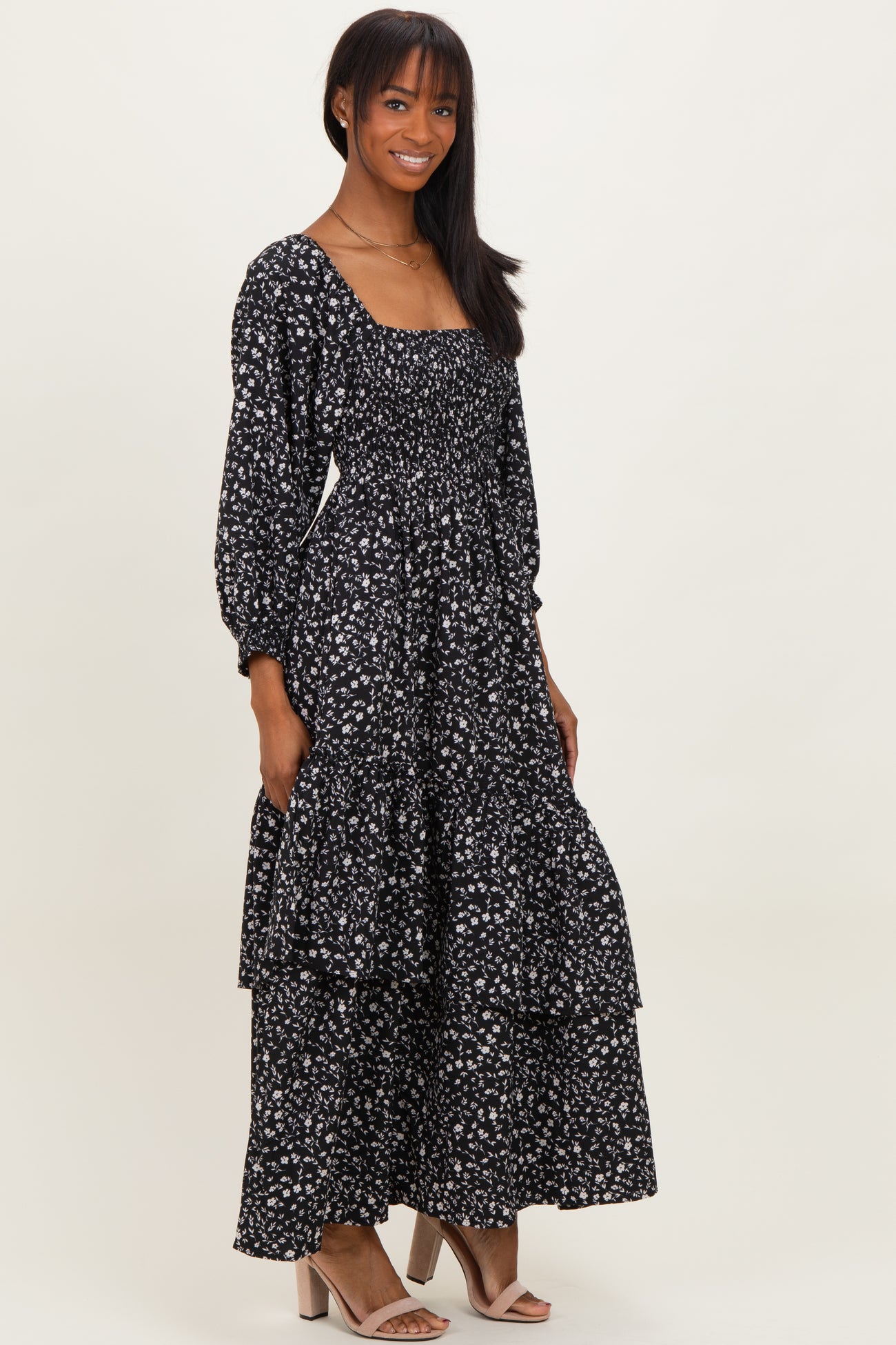 woman wearing a black floral long sleeve maxi dress with a smocked bodice and tiered skirt
