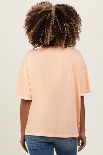 woman wearing a soft peach loose-fitting maternity top with short sleeves, view of the back
