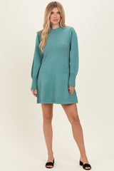 woman wearing a teal long sleeve sweater dress with puff sleeves and black slide sandals