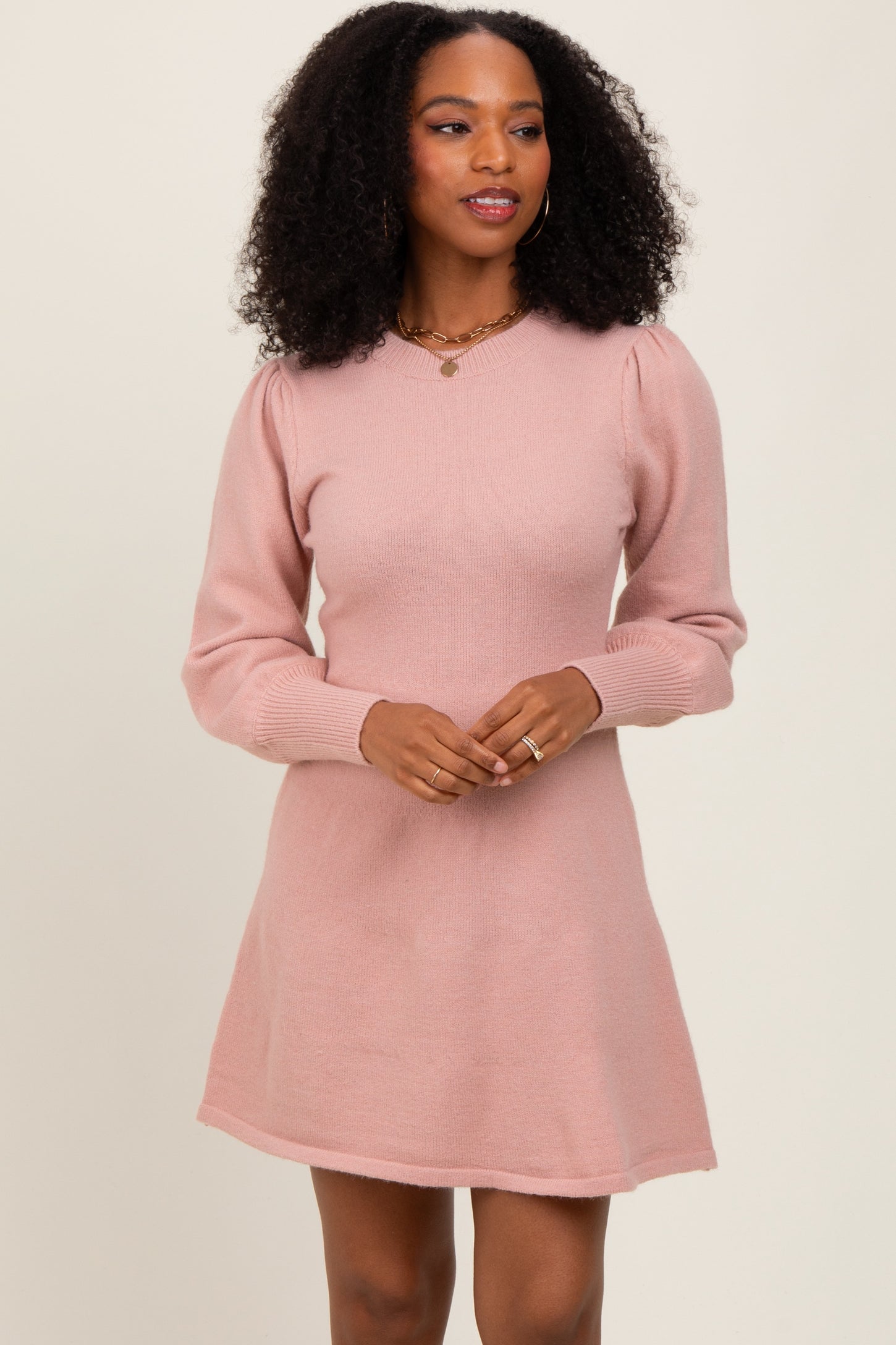woman wearing a light pink long sleeve sweater dress with a v-neck and puffed sleeves