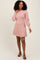 woman wearing a light pink sweater dress with puff sleeves and a round neckline, smiling while standing