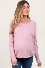 woman wearing a light pink maternity sweater with long sleeves and a visible baby bump
