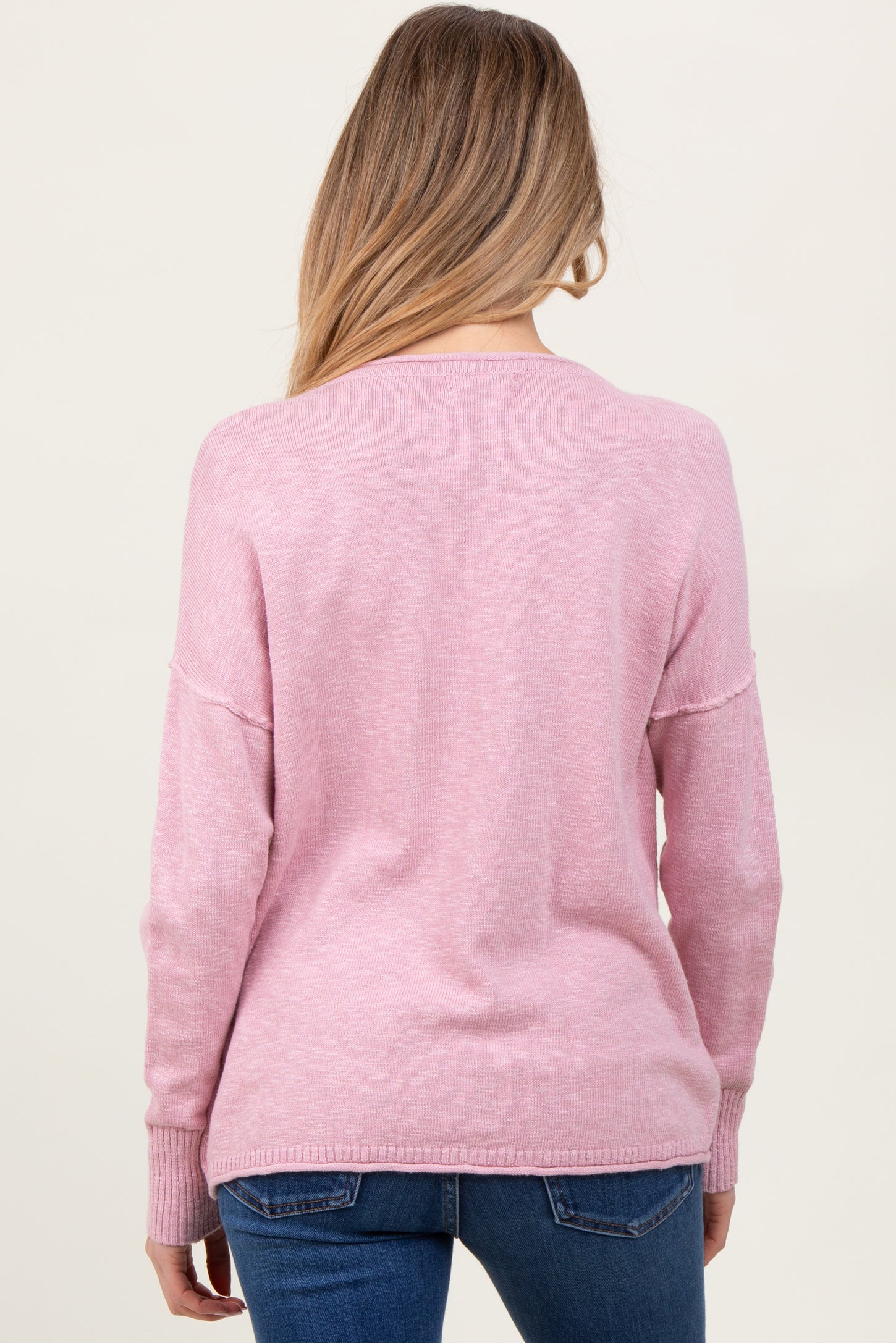 woman wearing a pink maternity sweater with a relaxed fit and long sleeves, viewed from the back