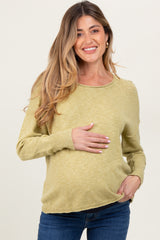 woman wearing a light green maternity sweater and holding her baby bump