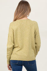 woman wearing a light green maternity sweater with a relaxed fit, seen from the back, paired with jeans