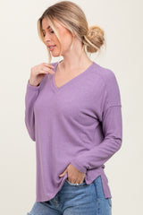 woman wearing a loose-fitting lavender long sleeve v-neck top with side slits, styled with light blue jeans