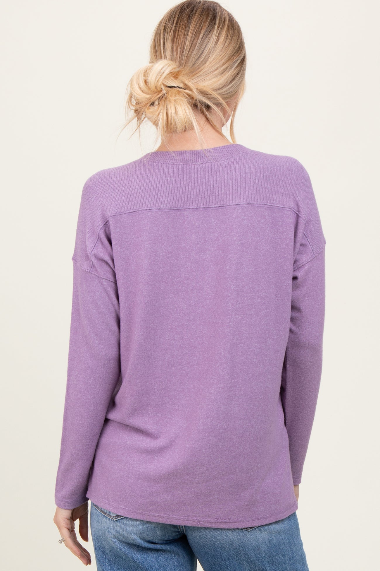 woman wearing a lavender long sleeve sweater with a relaxed fit and a dropped shoulder design, viewed from the back