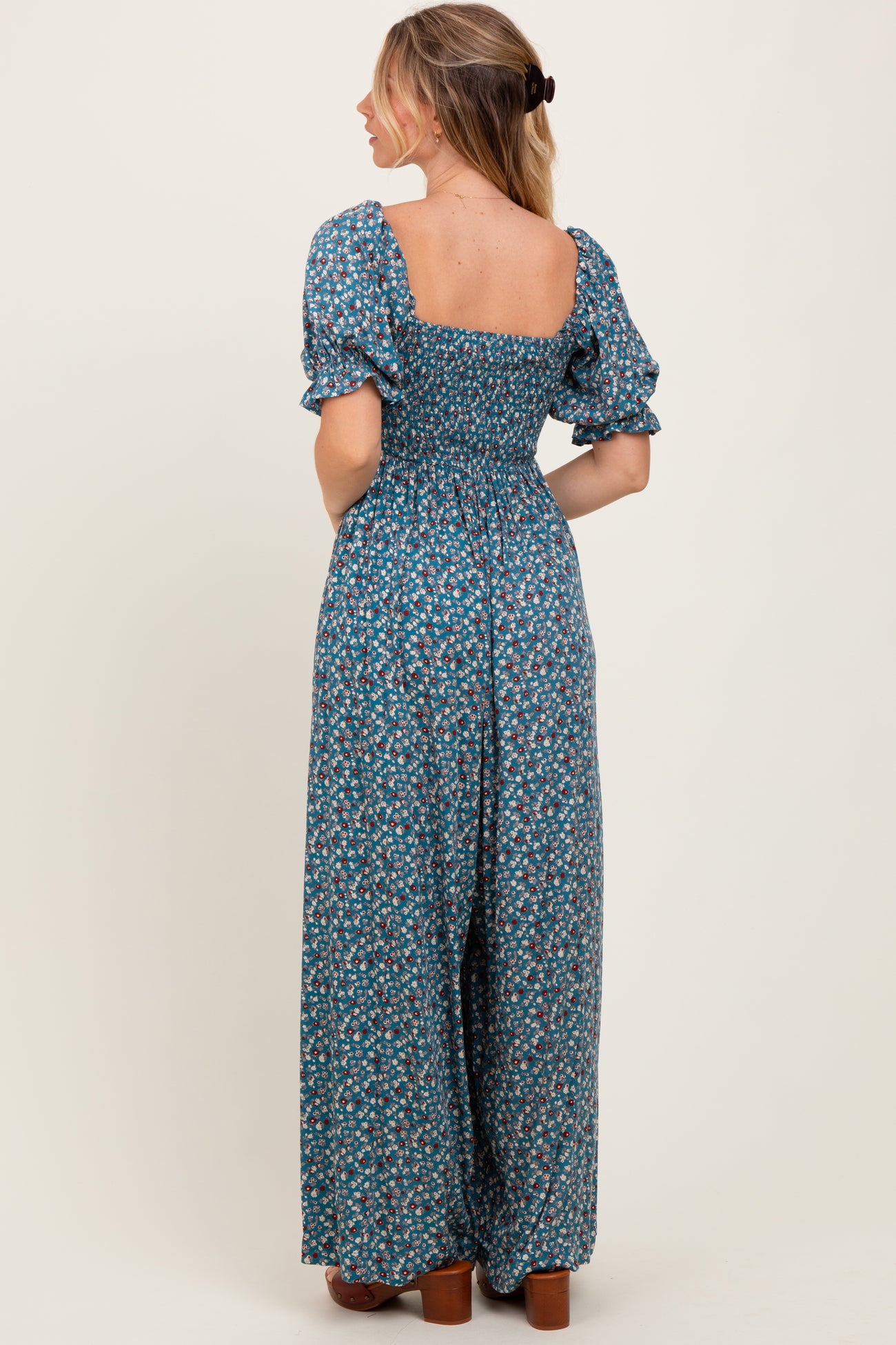 woman wearing a navy blue floral smocked maxi dress with puff sleeves, shown from the back