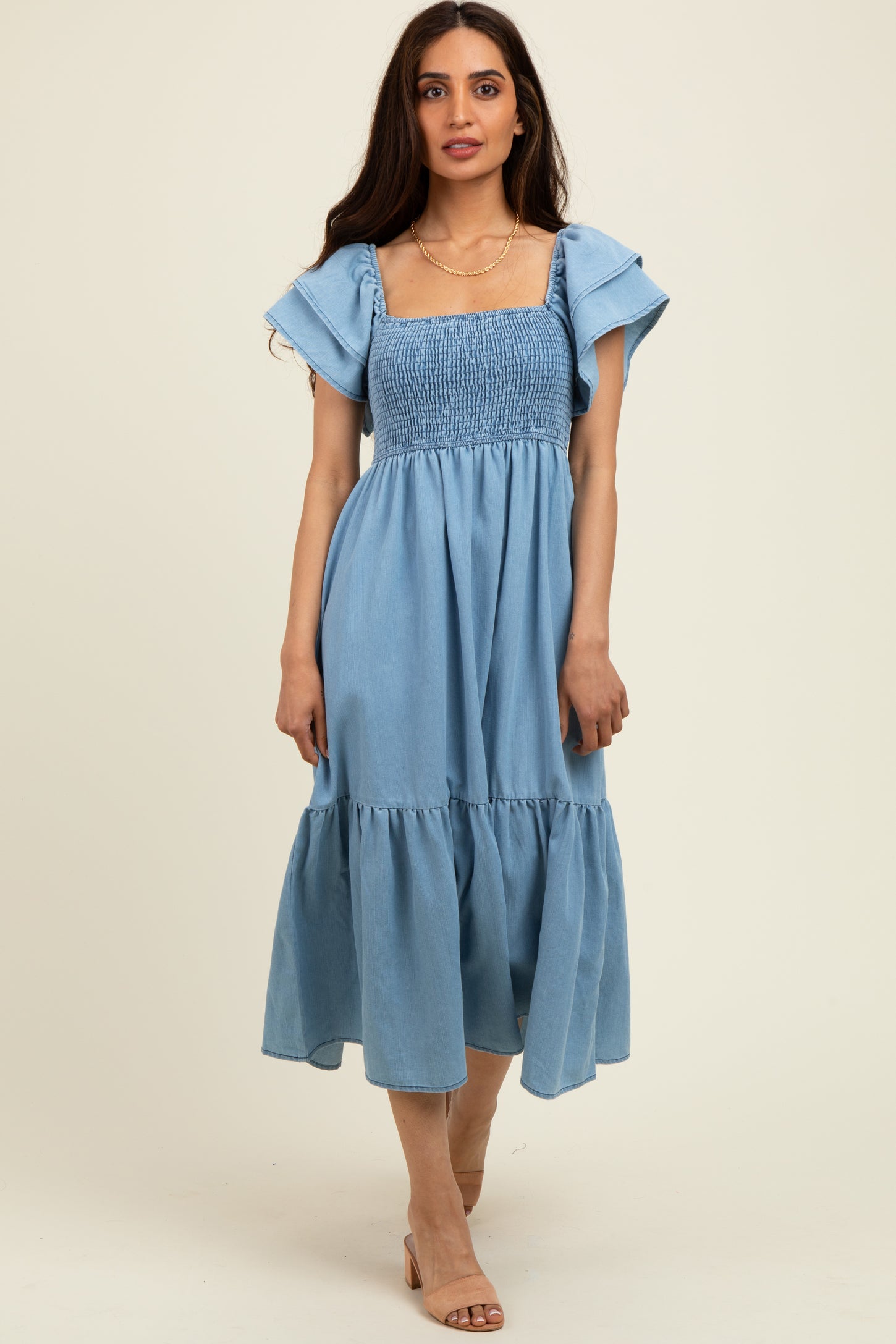 woman wearing a light blue smocked maxi dress with flutter sleeves and a tiered skirt