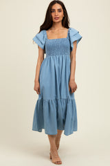 woman wearing a light blue smocked maxi dress with flutter sleeves and a tiered skirt