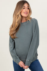 woman wearing a faded green maternity sweatshirt with a relaxed fit and a visible baby bump